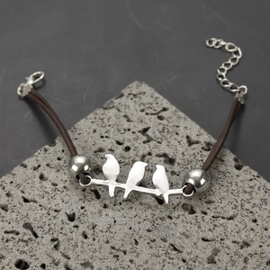 Detailed view of silver hummingbird charm bracelet on natural stone with leather strap