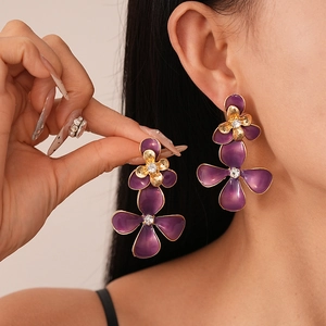 Vintage purple flower earrings with gold plating and rhinestones on model