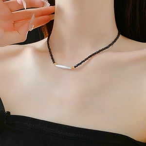 Close-up of French vintage black crystal necklace with pearl and gold accents on a model