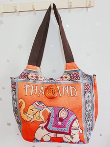 Detail der orangefarbenen Elefanten-Segeltuchtasche mit Holzknopf und Bestickung