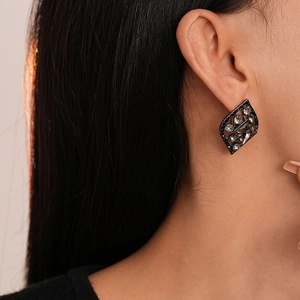Macro detail of dark diamond rhombus leaf earrings on model showcasing gothic luxury style
