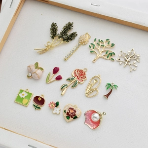 Assorted enamel plant charms including tulips and coconut trees in a wooden frame