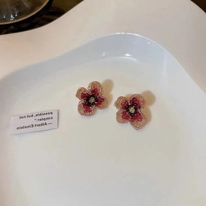 Close-up of floral crystal earrings with deep red gradient petals on a white tray