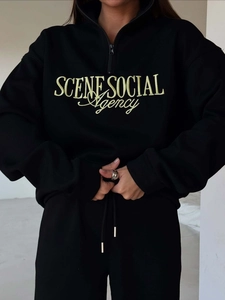 Detail of yellow embroidery on black half-zip sweatshirt with loose-fit athletic design