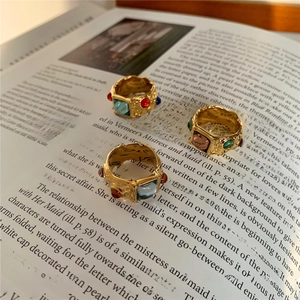 Close-up of vintage gold rings with colorful gemstones on an artistic magazine page