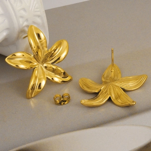 Détail de boucles d'oreilles fleur en acier inoxydable doré 18 carats sur socle gris