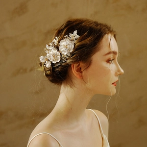 Vue détaillée d'un peigne à cheveux pour mariée avec fleurs blanches, perles et feuilles d'or