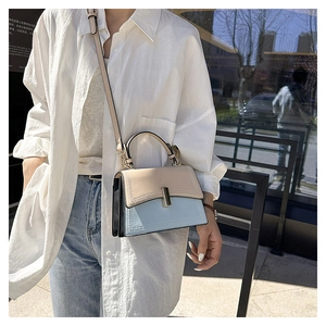 Photo en extérieur d'un sac bandoulière élégant tricolore beige et bleu avec rabat