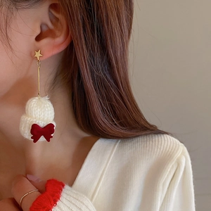 Detail showing red velvet bow and white fuzzy ball drop on gold star stud earrings
