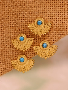 Macro detail of fan-shaped turquoise earrings with gold dot texture on rustic burlap