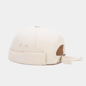 Close-up of beige PARIS embroidery on the folded brim of a canvas docker hat