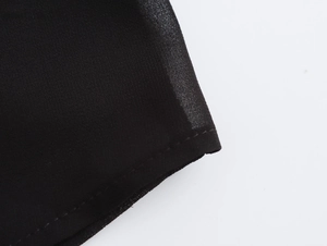 Detail view of neatly stitched seam and black chiffon fabric texture on this blouse