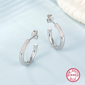 Detail view of S925 sterling silver hoop earrings with cubic zirconia on a wave background