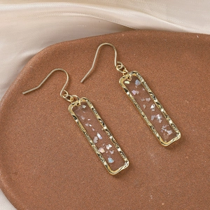 Macro shot of rectangular gold earrings with iridescent shell inlay on silk fabric