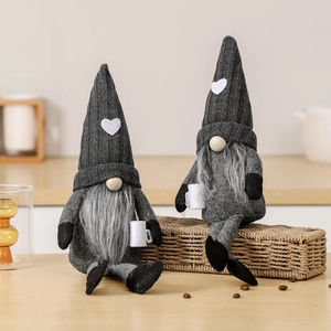 Pair of grey knitted heart gnome plush dolls with coffee mugs on wooden surface