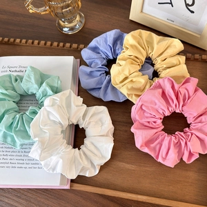 Set of 5 pastel solid color fabric scrunchies arranged on a rustic wooden tray