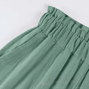 Dettaglio dei pantaloni in cotone e lino verde chiaro con vita elastica e volant fini