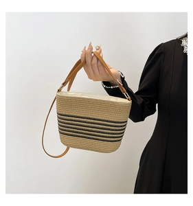 Detail of Korean style straw bucket bag with black stripes and brown leather strap