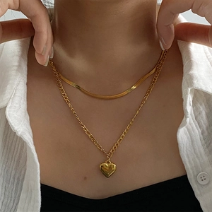 Close-up of double layered gold titanium necklace with heart pendant and snake chain