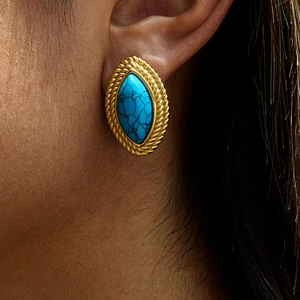 Bohemian gold woven earrings with oval turquoise stone worn by a female model