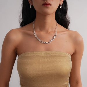 Detail view of a luxury silver-toned necklace and square diamond earring set on a model