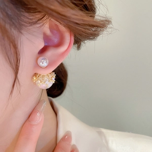 Detailed view of luxury gold-plated pearl stud earrings worn with crown-shaped hollow design