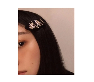 Close-up of black hair clip with silver floral pattern worn on model's side hair
