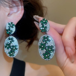 Detailed macro shot of elegant green zircon flower drop earrings with crystal pavé.