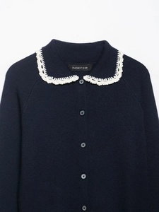 Detail of navy knit cardigan with white crochet Peter Pan collar and black buttons