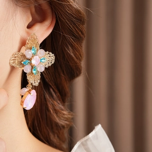 Close-up of vintage floral earrings with pink and blue crystals on a model