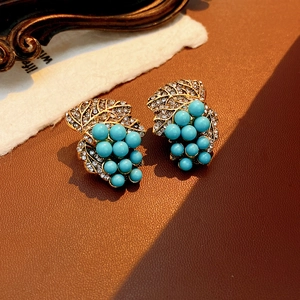Close-up of vintage grape earrings with turquoise beads and inlaid sparkling crystals