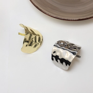 Detailed close-up of textured gold and silver irregular hammered metal hair clips