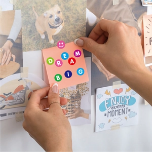 Close-up of colorful circular alphabet stickers spelling DREAM BIG on a pink note