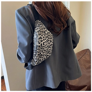 Detailed view of leopard print crossbody bag with adjustable wide strap on a grey blazer