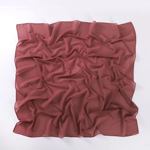 Detailed texture of dusty pink chiffon square scarf showing soft artistic folds on white