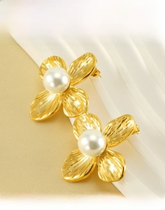 Macro shot of titanium steel flower earrings with white pearl center in golden finish