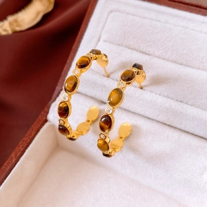 Close-up of C-shaped tiger eye earrings with white rhinestones in a velvet jewelry box