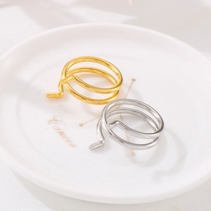 Close-up of spiral gold and silver stainless steel rings on a ceramic jewelry tray