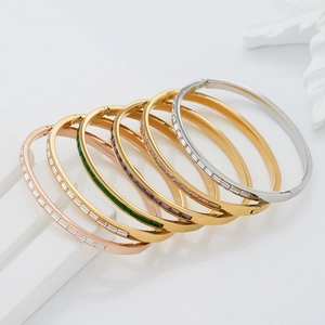 Stack of gold, silver, and rose gold stainless steel bangles with colorful gemstones