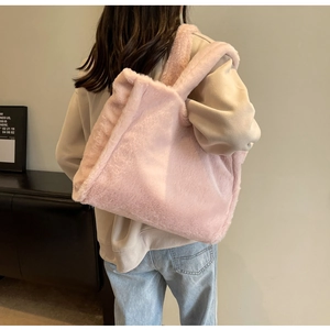 Vue détaillée d'un cabas rose en peluche porté à l'épaule montrant sa taille et sa texture