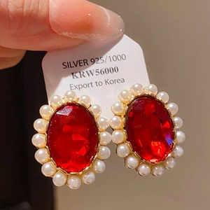 Close-up of S925 silver stud earring with vintage red oval gemstone and pearl halo