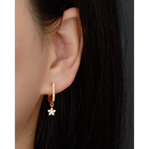 Close-up of gold U-shaped hoop earring with sparkling zircon star pendant on ear