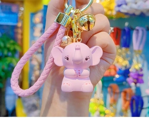 Close-up of pink elephant keychain with crown, braided rope and golden bell detail