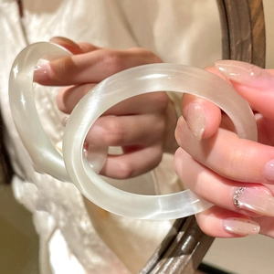 Close-up of a translucent white glass bangle with minimalist geometric design held in hand