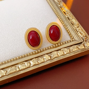 Close-up of vintage oval red gemstone earrings with golden rope borders on leather