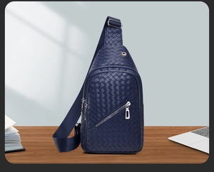 Detail of navy blue woven leather sling bag featuring silver zipper on wooden table