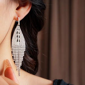 Close-up of model wearing sparkling rhinestone triangle tassel earrings with fringe detail