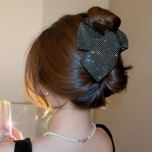 Sparkling rhinestone bow hair claw clip styled on elegant brown updo hairstyle