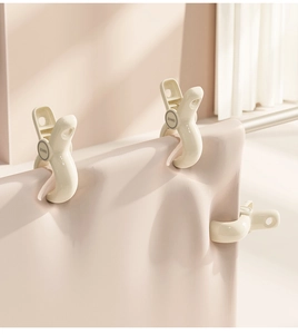 Detailopname van grote crèmekleurige winddichte clips die een dekbed op een stang klemmen