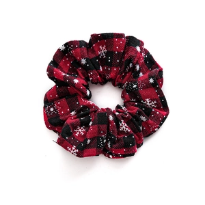 Red and black plaid Christmas scrunchie with white snowflake patterns on a white background